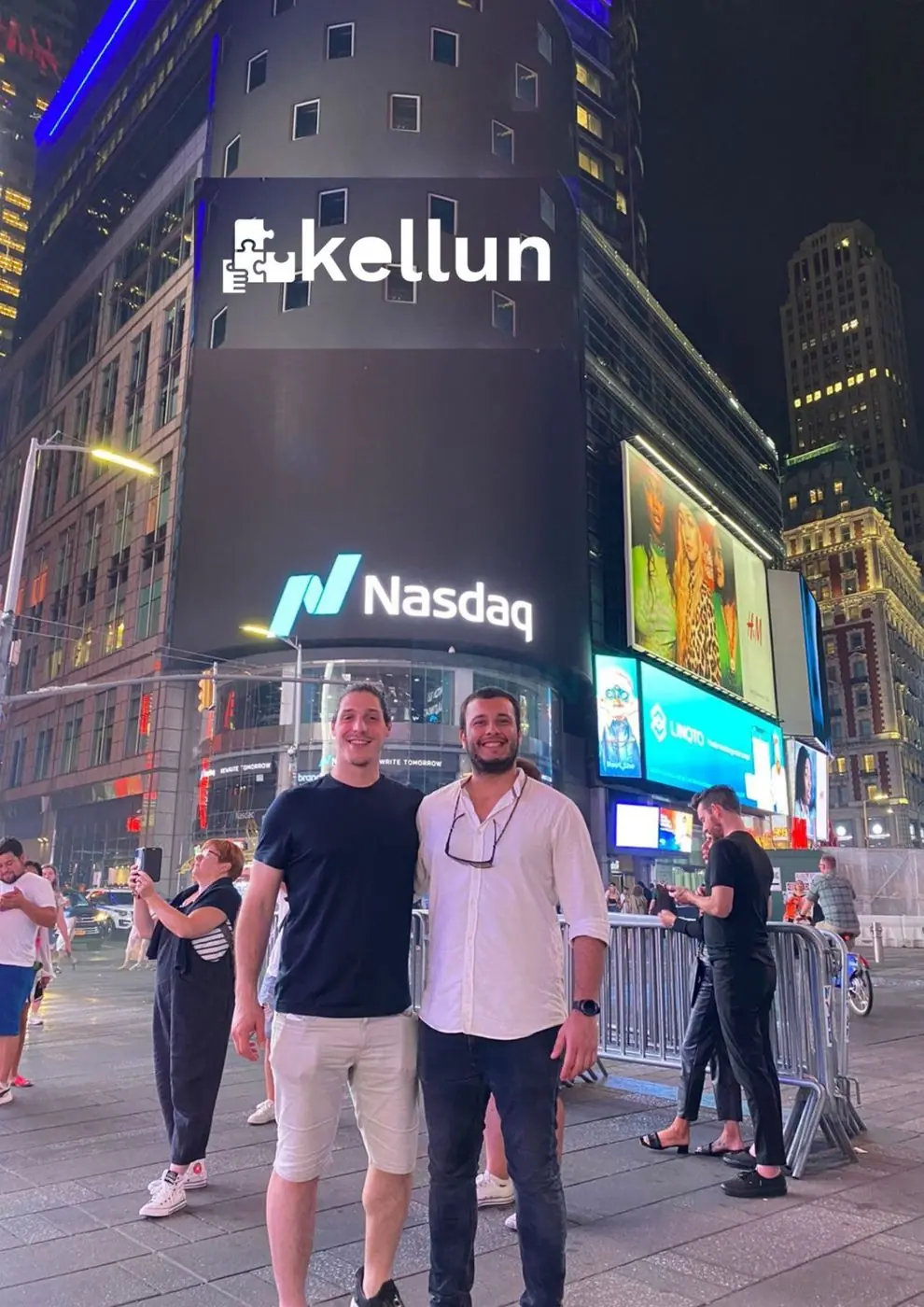2 personas frente a la fachada del Nasdaq en Times Square, Nueva York.