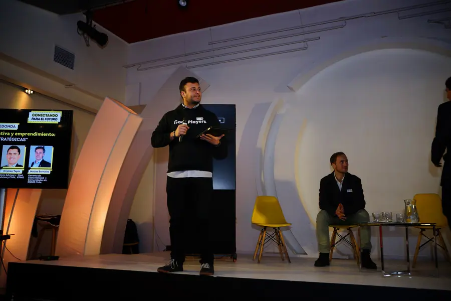 Tomás Ffrench-Davis presentando de pie en una sala ante público sentado.