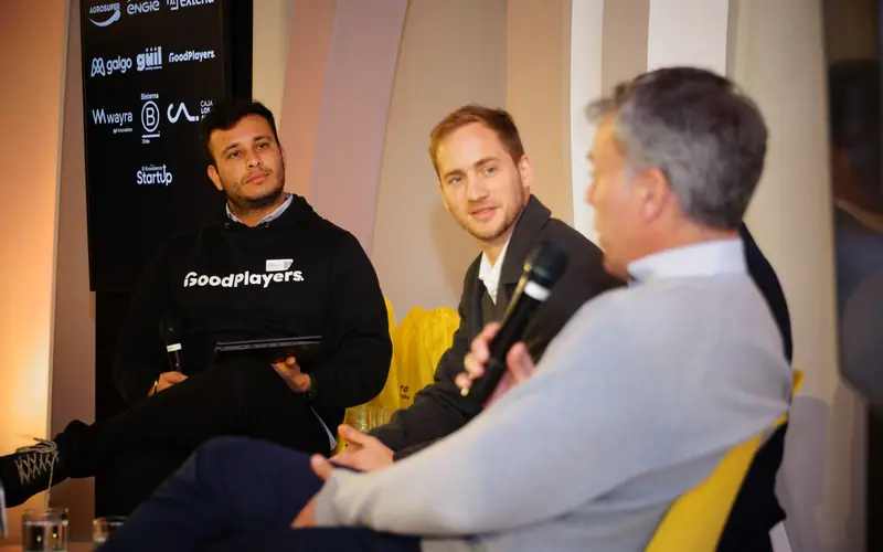3 personas conversando sentadas en un panel, una de ellas con el micrófono en la mano.