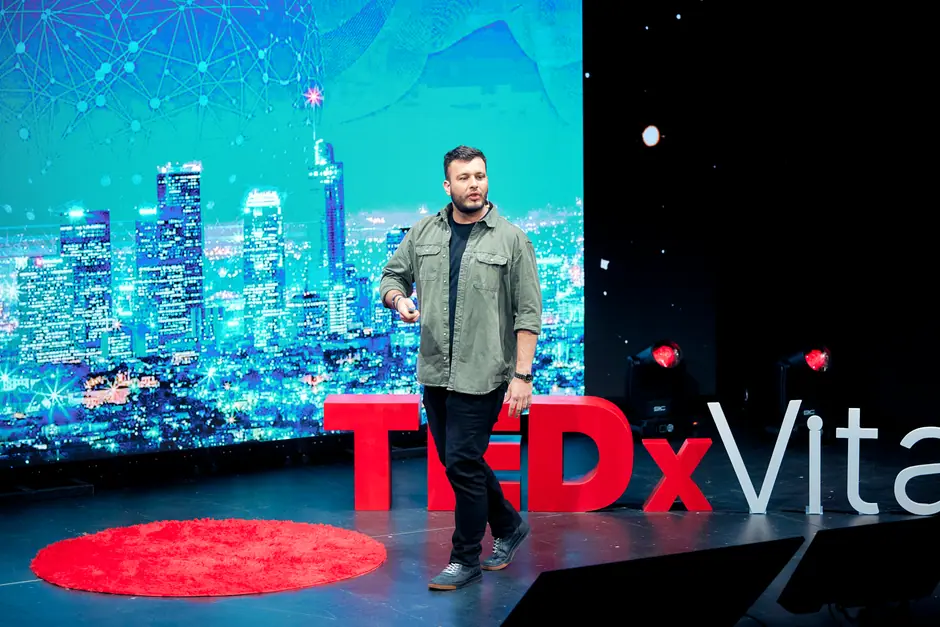 Tomás Ffrench-Davis en el escenario de TEDxVitacura, ante una lámina de una ciudad iluminada de noche.